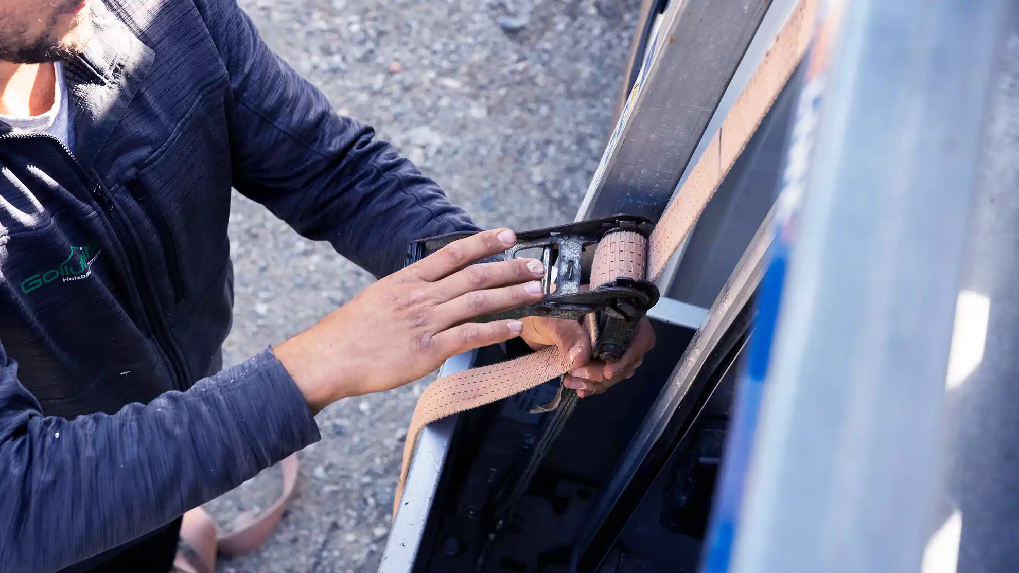 Load securing strap being tightened